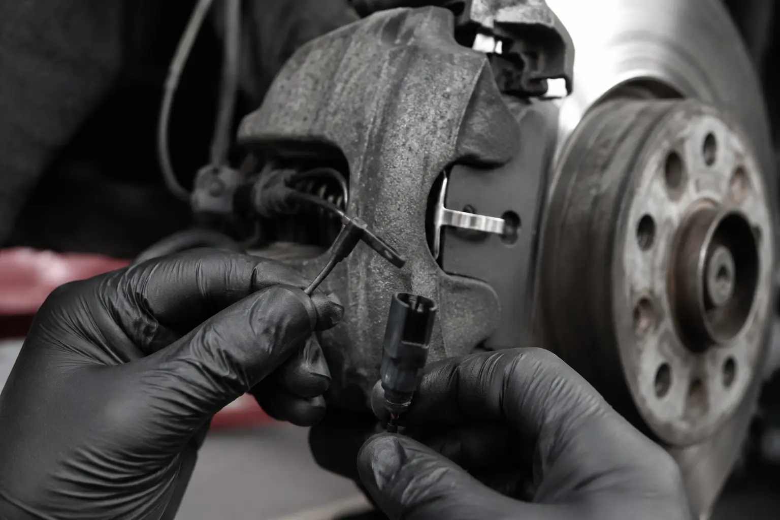 Brake wear sensor and connector checked during an Audi brake service
