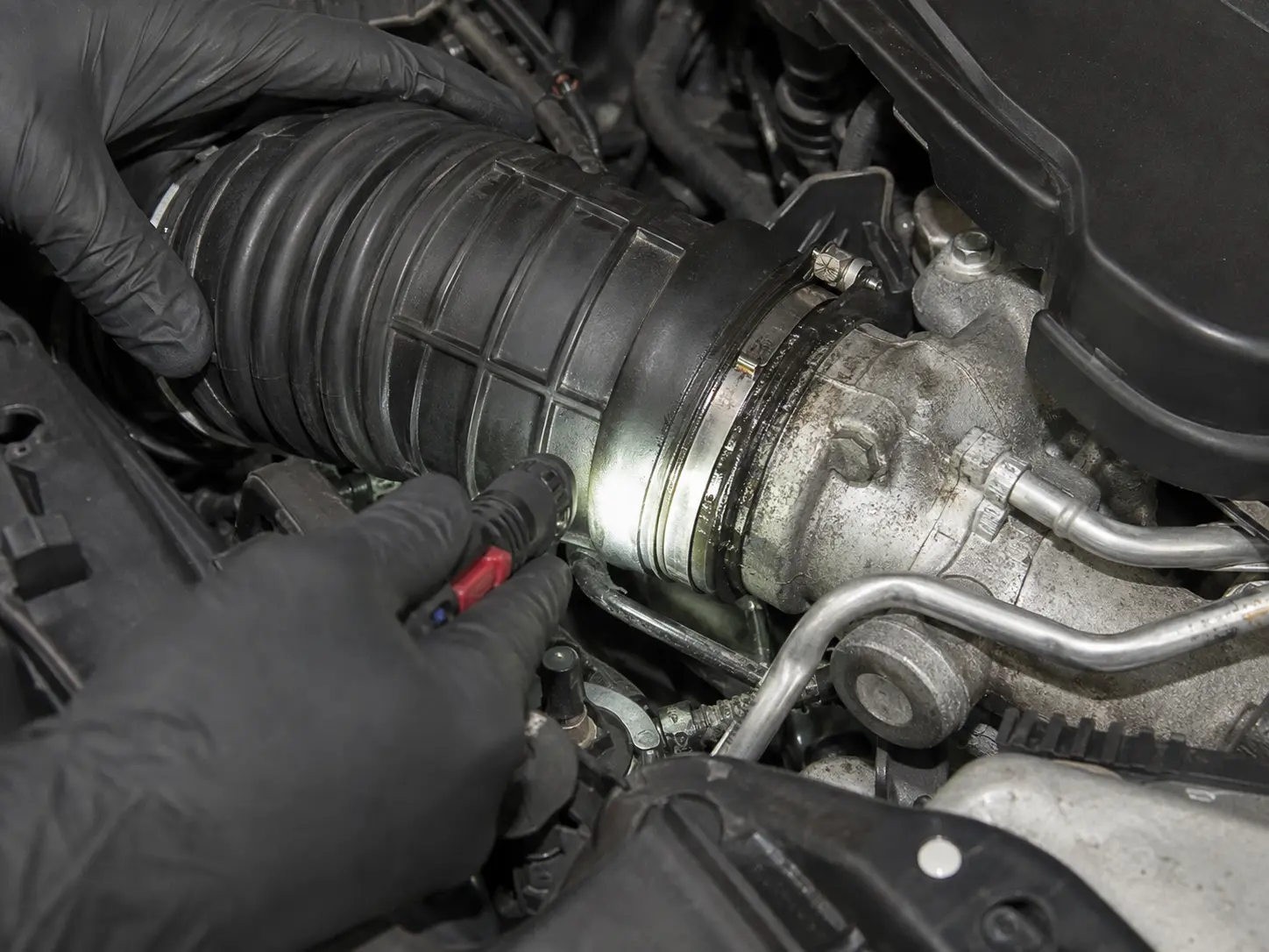 Technician inspecting an Audi charge-pipe joint and seal for leakage