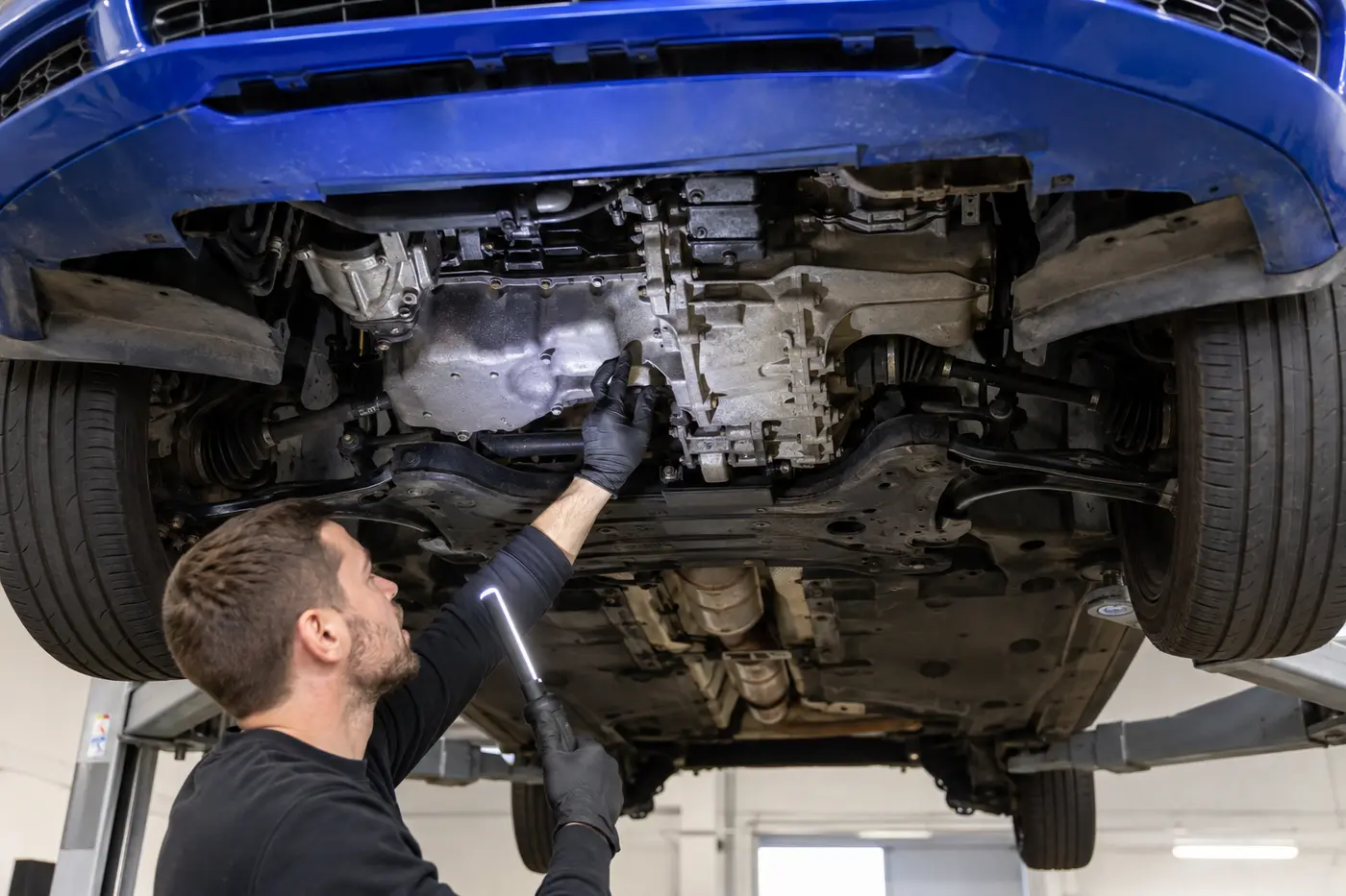 Technician tracing the gearbox and front drive shafts beneath an Audi