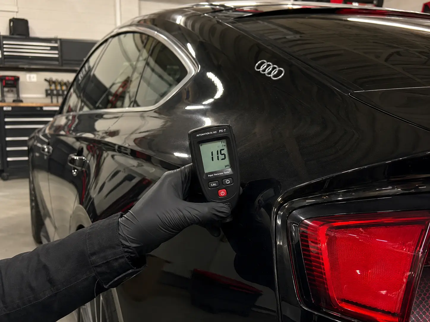 Paint-thickness gauge contacting an Audi rear body panel