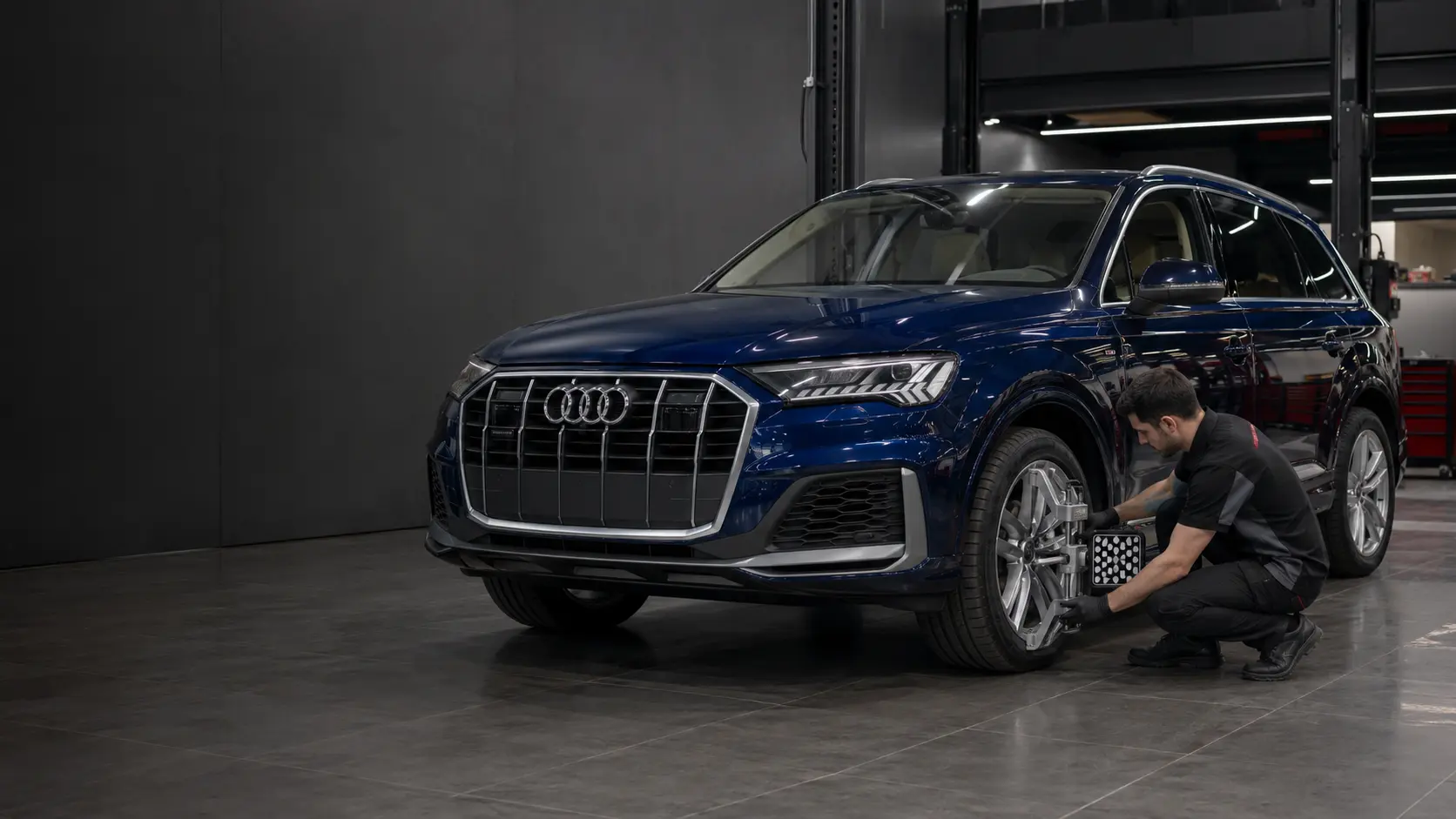 Sapphire blue Audi Q7 with factory four-ring emblem undergoing ride-height inspection in a Dubai workshop