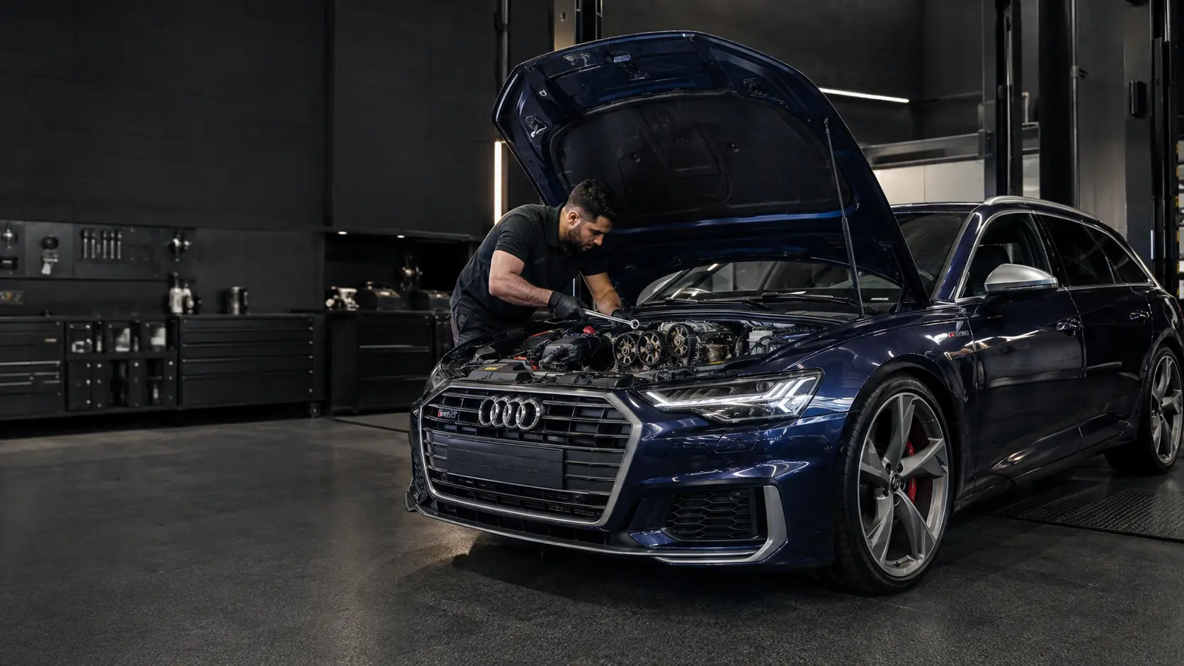 Technician working at the timing side of an Audi engine in a workshop