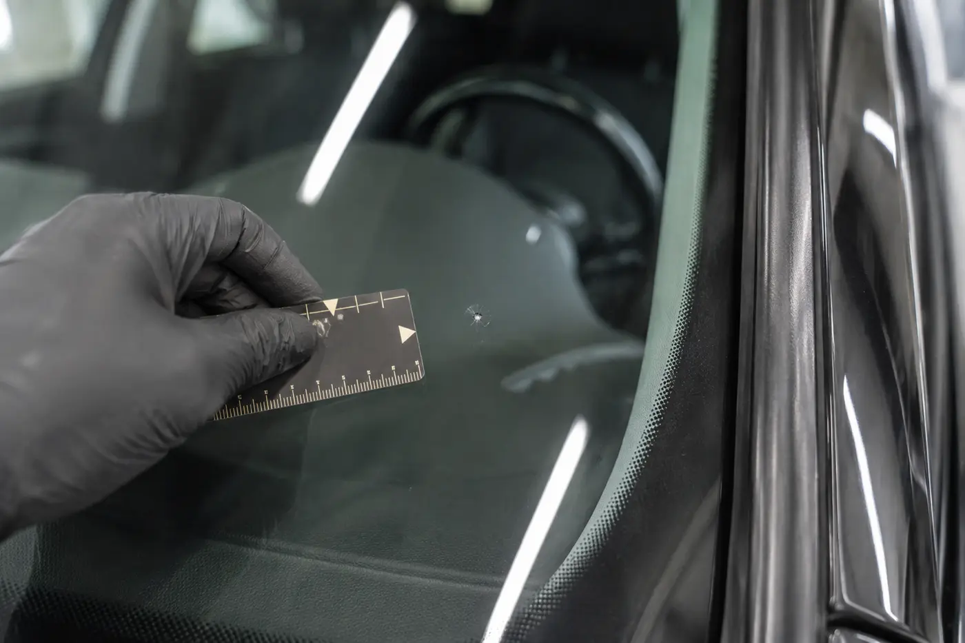 Close inspection of a small Audi windshield chip with a scale